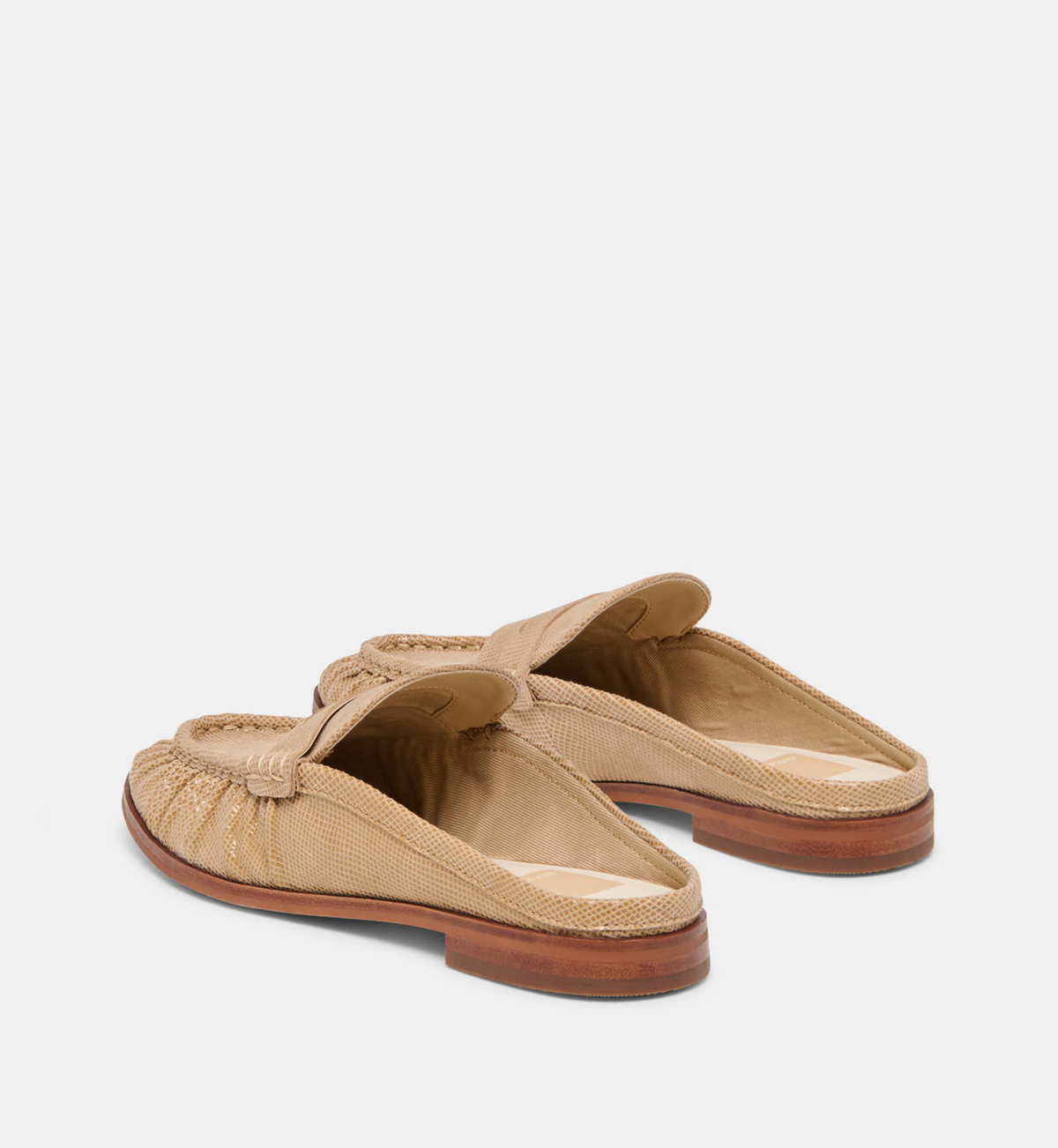 A pair of Dolce Vita Betzy beige woven leather mule loafers with a braided strap detail across the top, shown from a three-quarters angle on a light gray background.