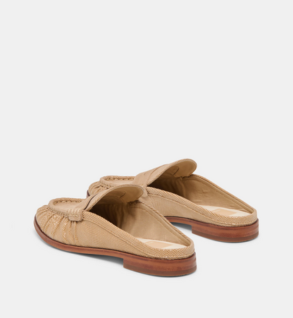 A pair of Dolce Vita Betzy beige woven leather mule loafers with a braided strap detail across the top, shown from a three-quarters angle on a light gray background.