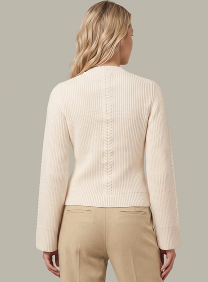 A woman shown from the back wearing a cream ribbed knit 525 America cardigan with textured sleeve panels and beige trousers, against a solid light gray background.