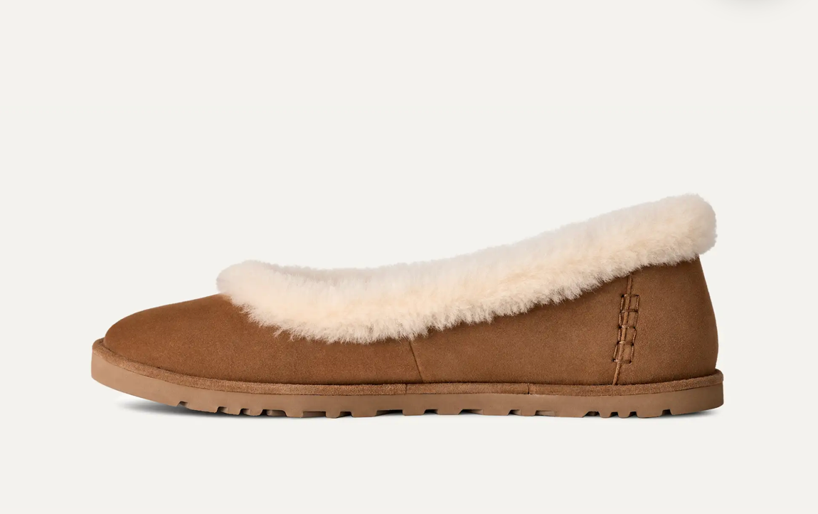 A single tan suede UGG ballet flat with a fluffy cream shearling lining, shown in a side profile against a clean off-white background.