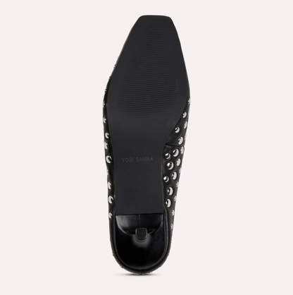 The black sole of a Yosi Samra Tribeca shoe, featuring silver metal studs along the side and a textured rubber outsole, shown against a light off-white background.