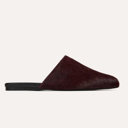 A single Yosi Samra Waverly dark burgundy hair-on-hide mule slipper with a black sole, shown in profile against a light off-white background.