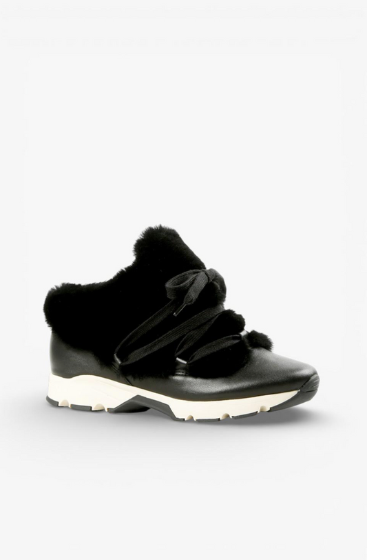 A black winter sneaker featuring a faux-fur collar, decorative faux-leather straps, and a chunky white and black sole, shown against a plain light gray background.