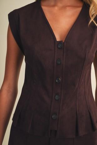 A close-up of a model wearing a sleeveless dark brown vest with a V-neckline and a vertical row of dark buttons down the front.