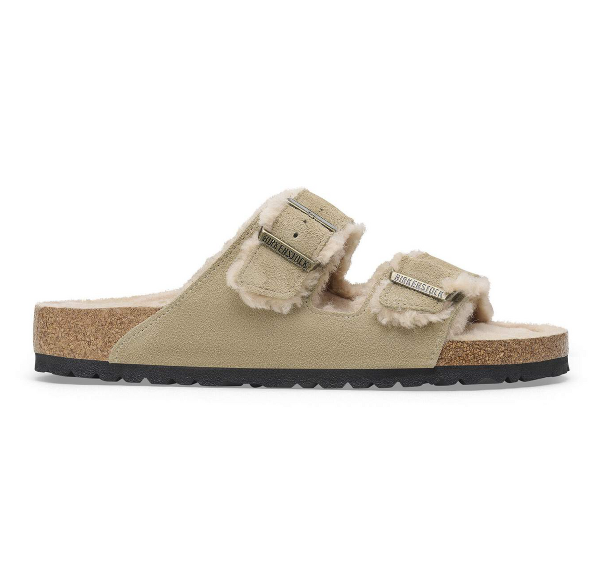 A pair of Birkenstock Arizona Shearling slip-on sandals in beige faux leather with fluffy cream shearling lining, cork midsoles, and black outsoles, shown from a side profile on a white background.