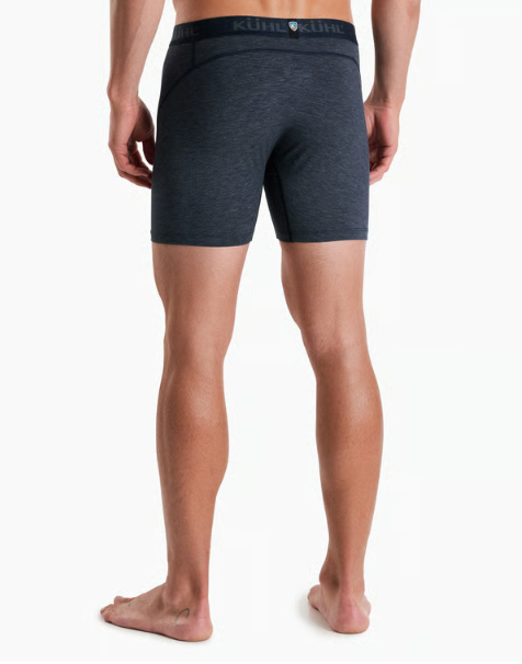 Rear view of a man wearing dark heather gray boxer briefs with a visible KUHL waistband, standing barefoot against a light gray studio background.