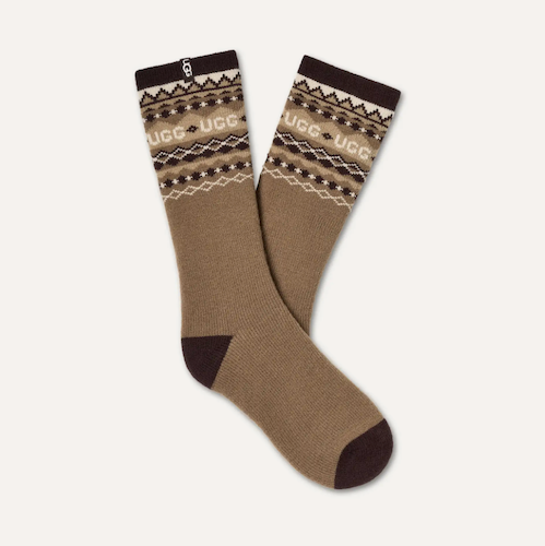 A pair of UGG crew socks in a warm taupe-brown color, featuring a dark brown heel and toe, and a patterned cuff with the brand name 'UGG' and its logo printed in cream and brown.