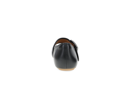 A single Dansko Matilda black leather flat shoe shown from the back, featuring a strap with a silver buckle and a light tan outsole, set against a plain white background.
