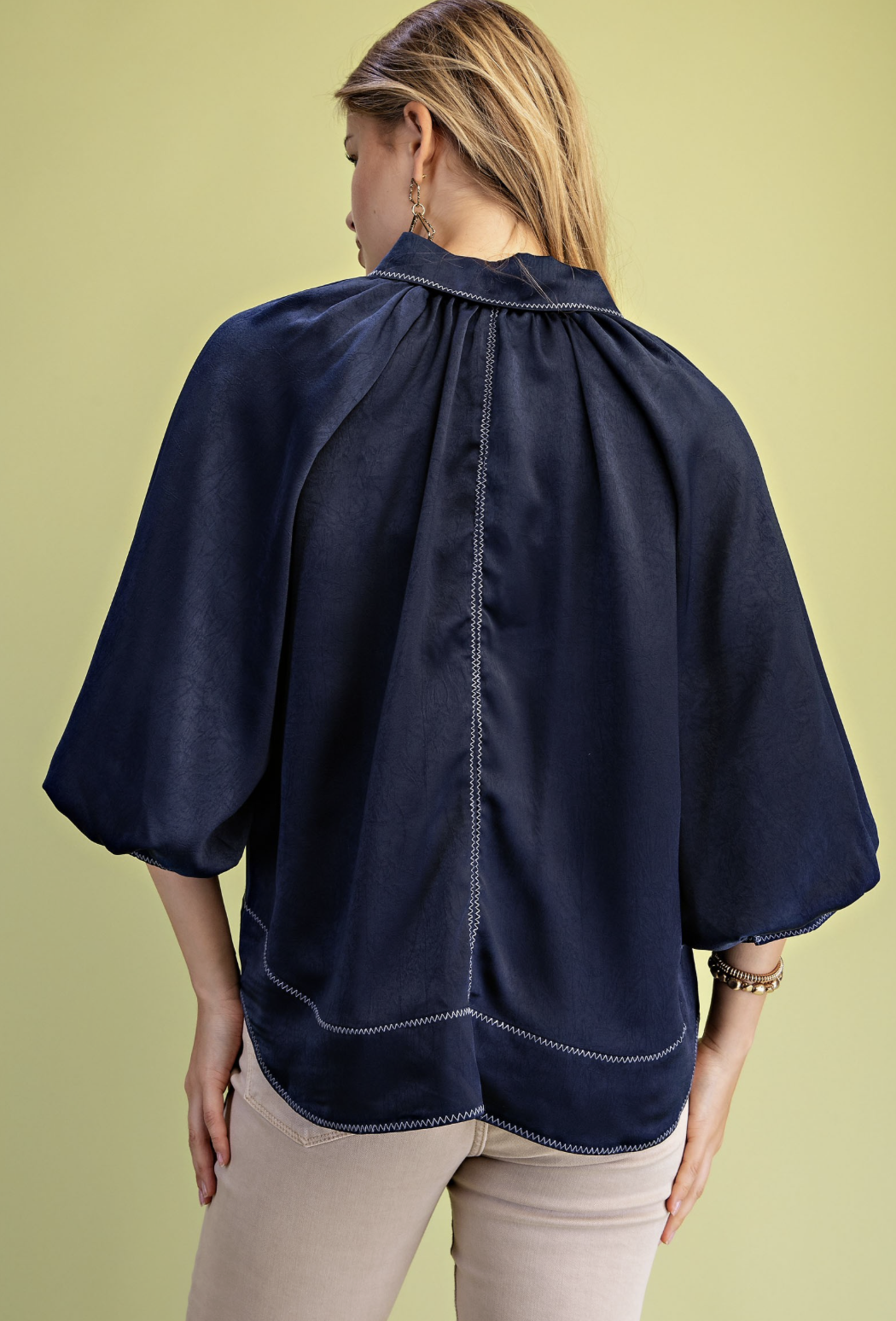 Satin blouse in brown or navy with voluminous balloon sleeves, zig zag stitching and a smooth draped silhouette.